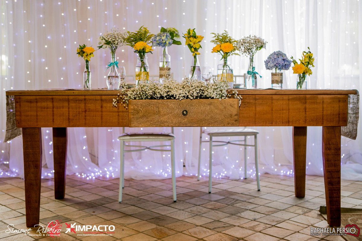 Mesa dos noivos de madeira com arranjo de garrafinhas e mosquitinhos na gaveta
