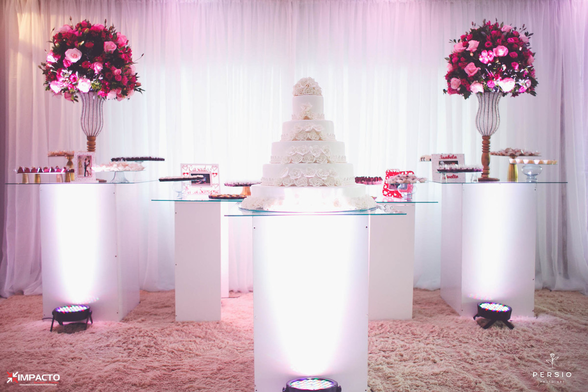 Mesas dos doces e bolo de vidro com iluminação e arranjos de flores marsala
