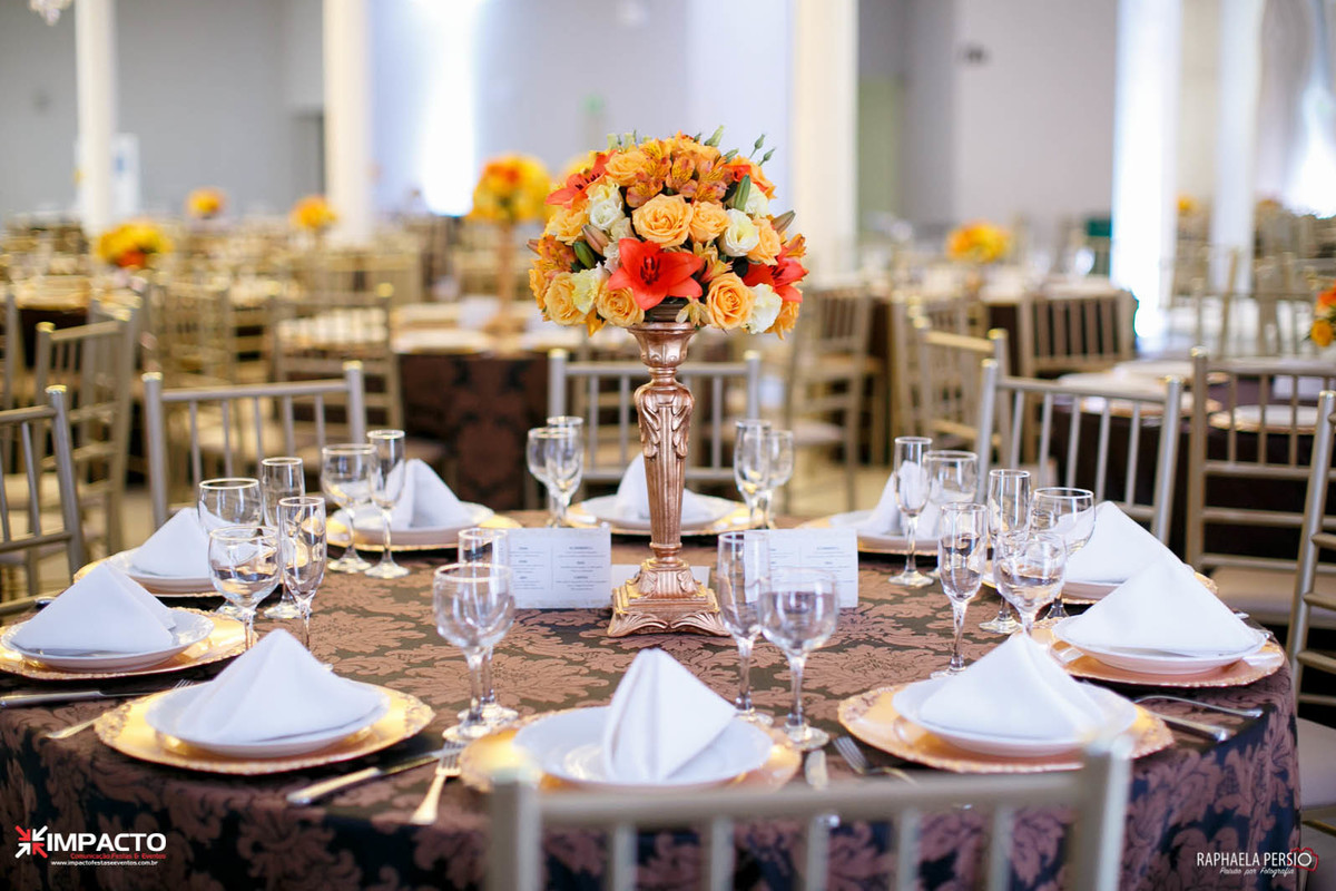 centro de mesa casamento base dourada com flores em tons laranja e amarelo