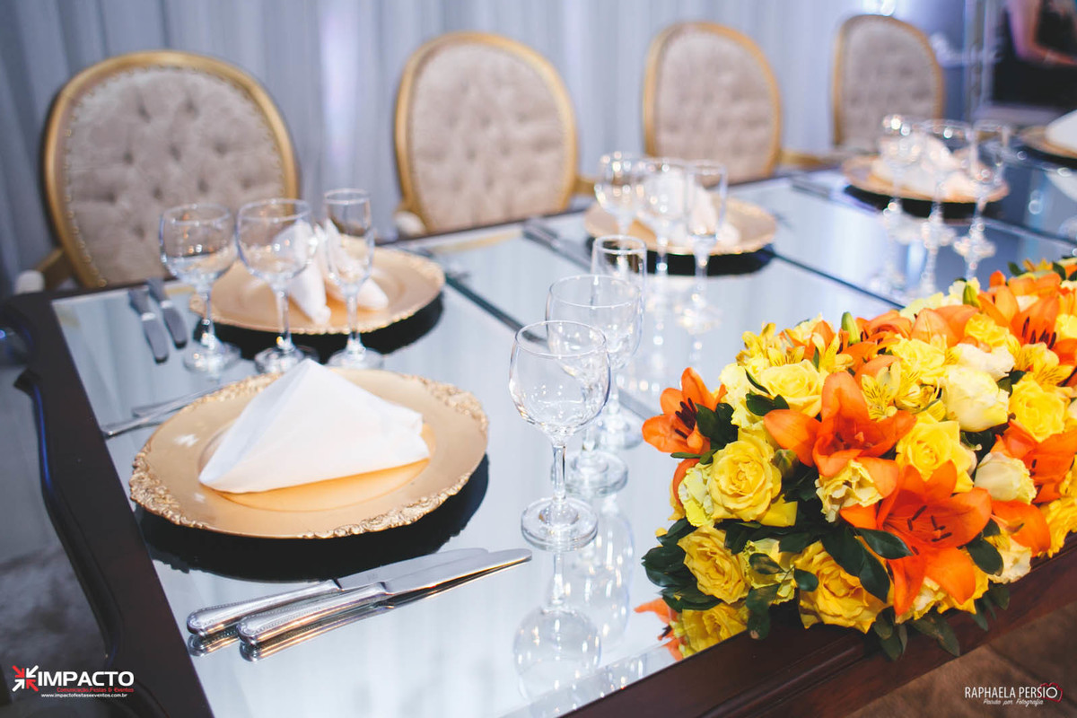 Mesa dos noivos espelhada com sousplat dourado e arranjo laranja e amarelo