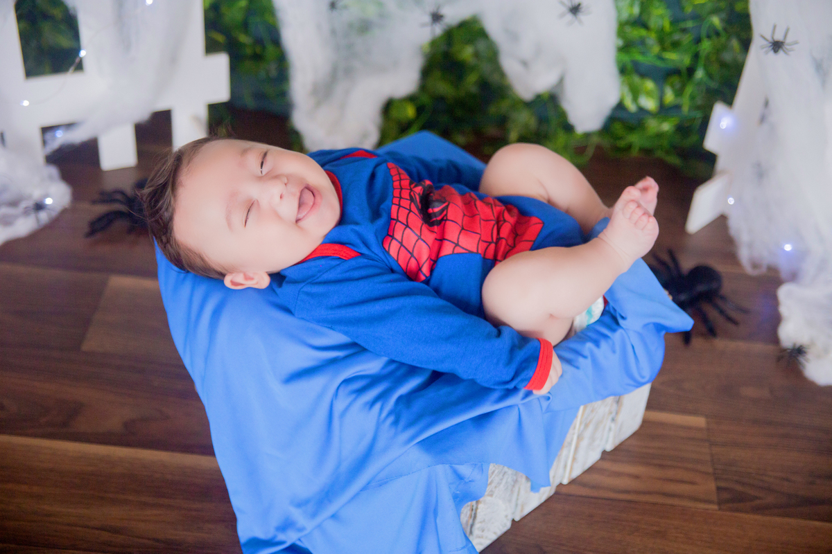 o bebê sorri para a fotógrafa em sua sessão de acompanhamento mensal