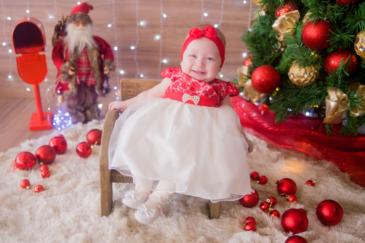 a bebê sorri para a fotógrafa em sua sessão de natal