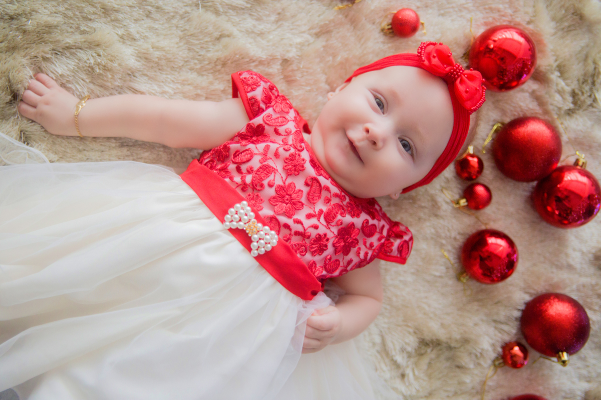 a bebê sorri deitada no cenário de natal