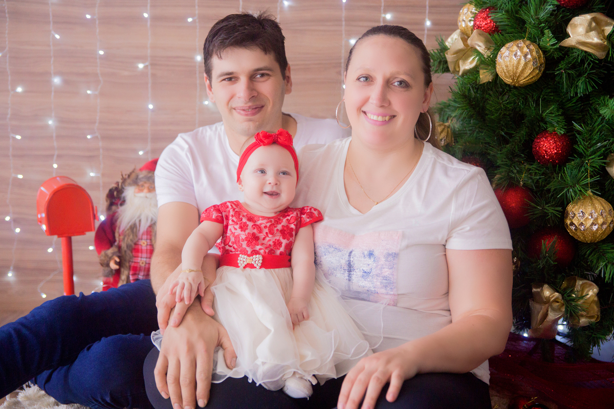 a família sorri para fotógrafa no cenário de natal