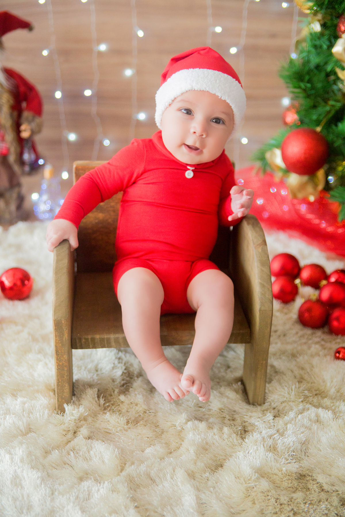 o bebê se segura no banquinho em sua sessão de natal