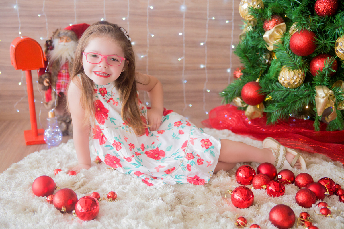 a menina faz pose para a fotógrafa em suas fotos natalinas