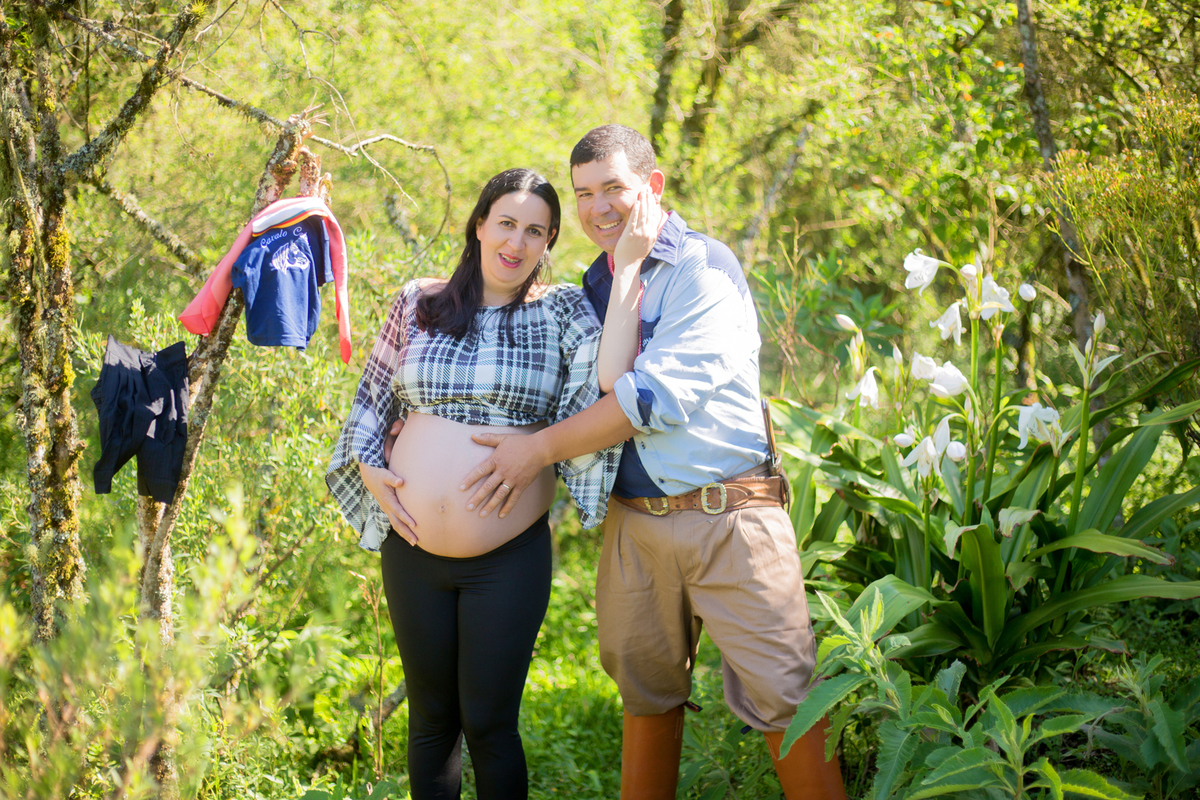 os pais exibem a pilcha do bebê que está a caminho em sua sessão fotográfica de gestante