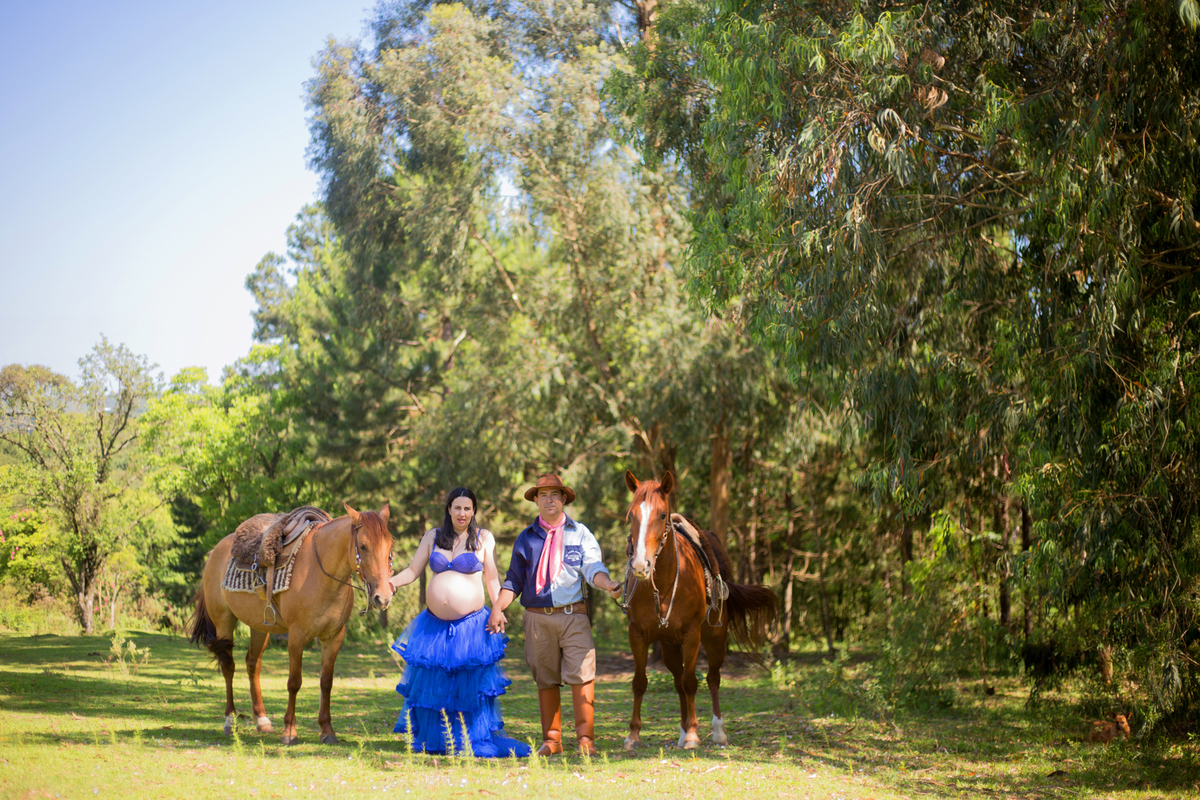 o casal e os cavalos posam para a fotógrafa na sessão de fotos de gestamte