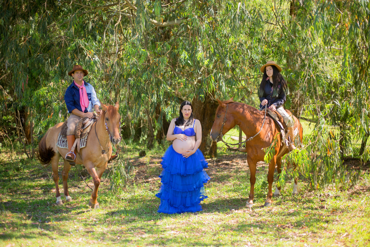 a gestante está de pé, olhando para a fotógrafa