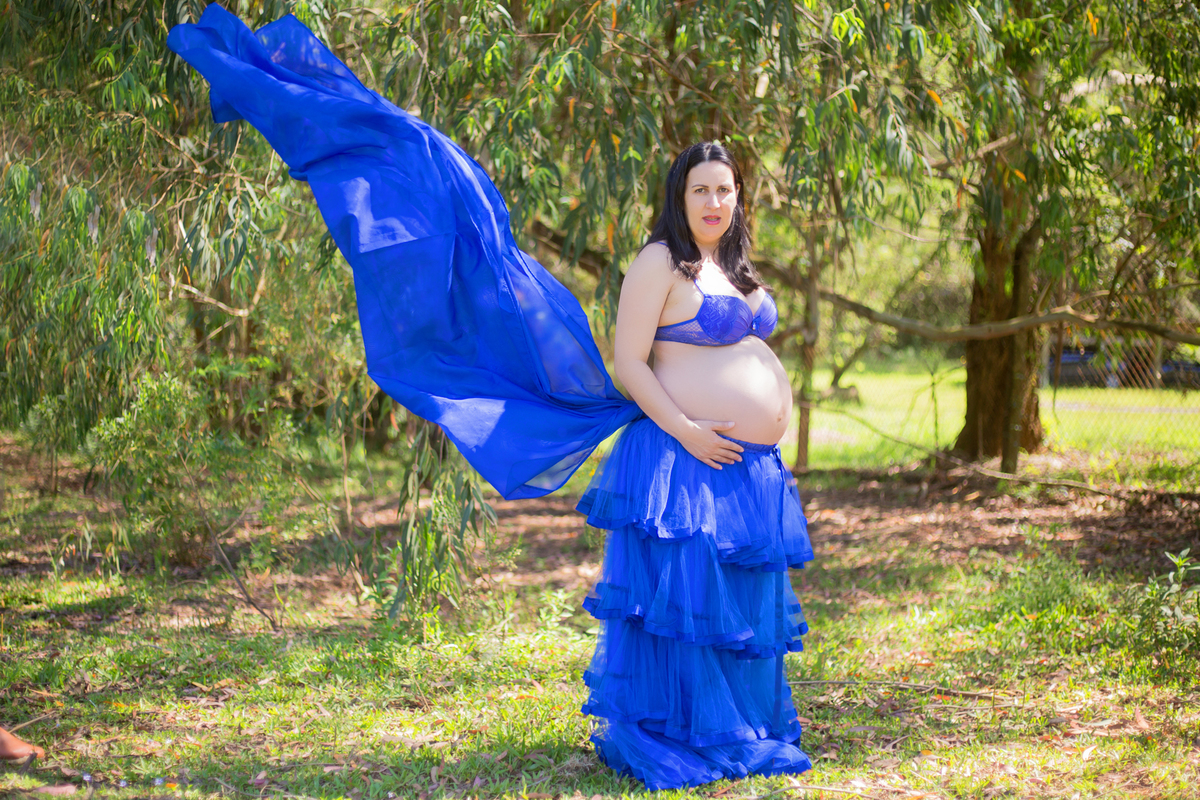 o véu do figurino de gestante voa, enquanto a fotógrafa de gestante clica