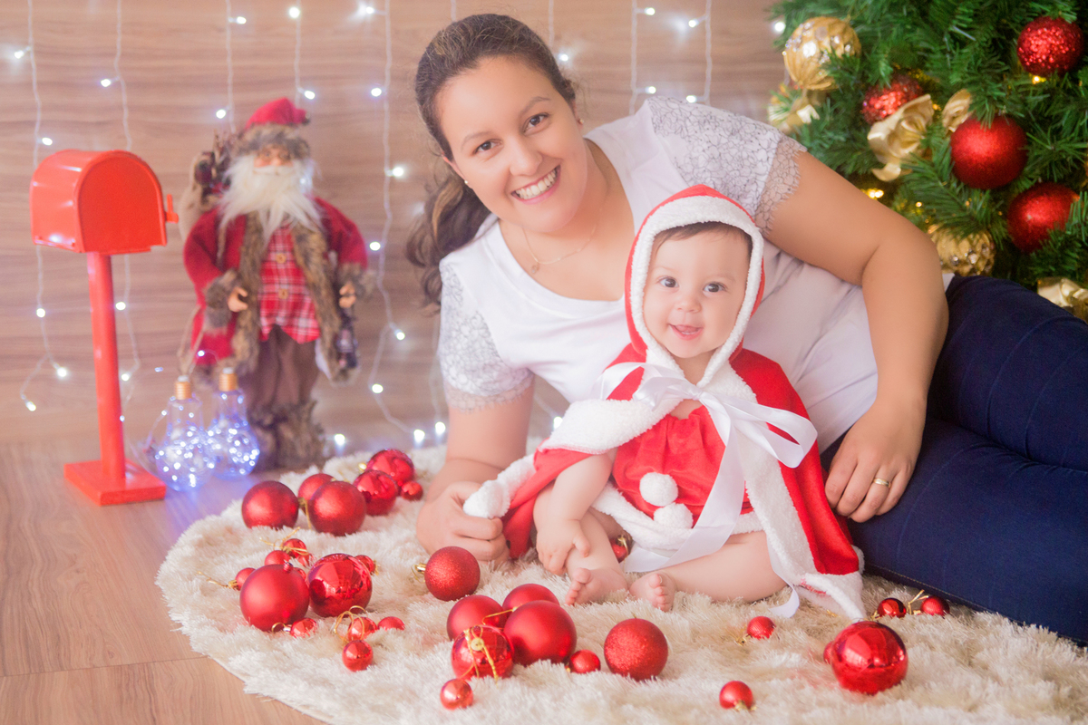 bebê e mamãe sorriem para a foto em sessão de fotos natalinas