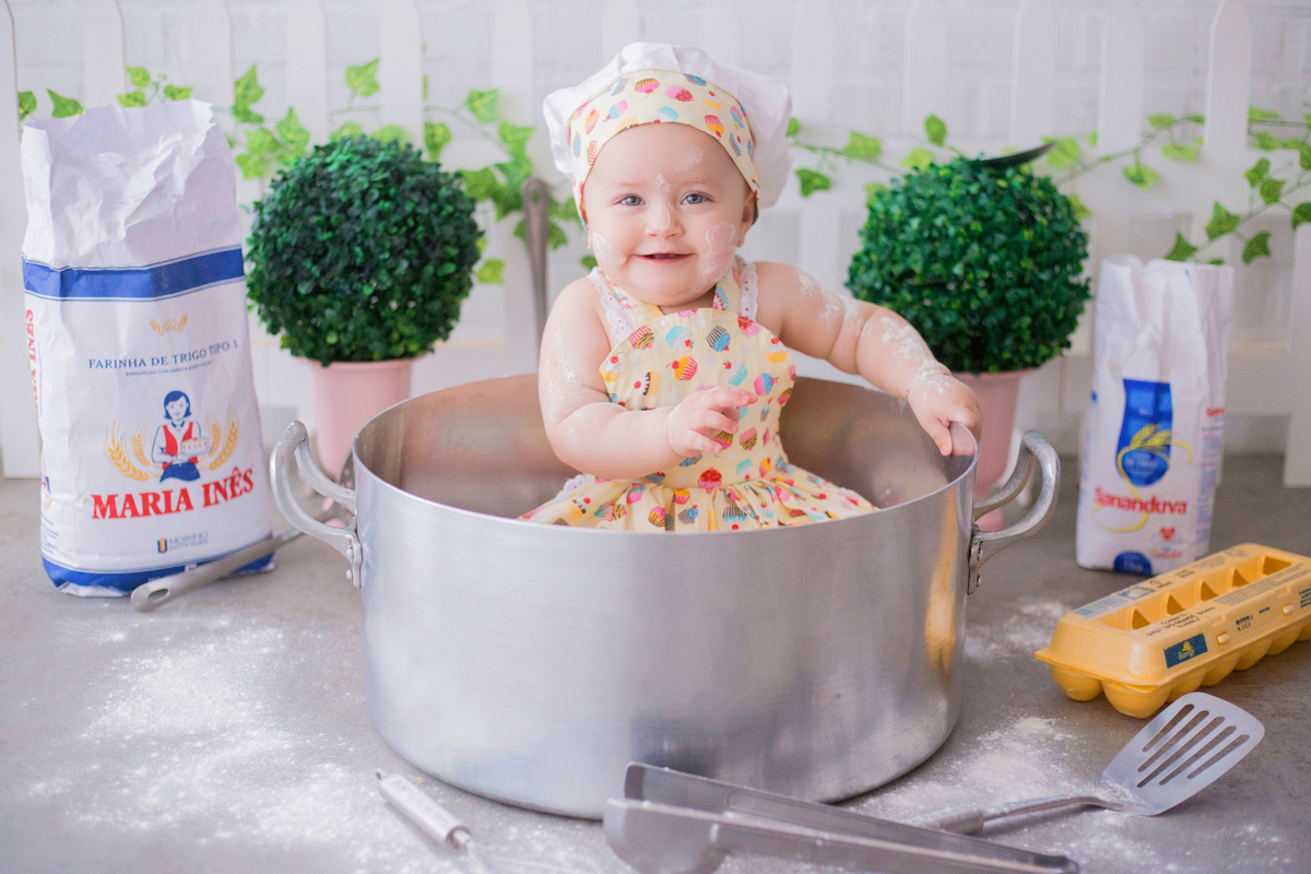 a bebê sorri dentro da panela em sua sessão de acompanhamento mensal