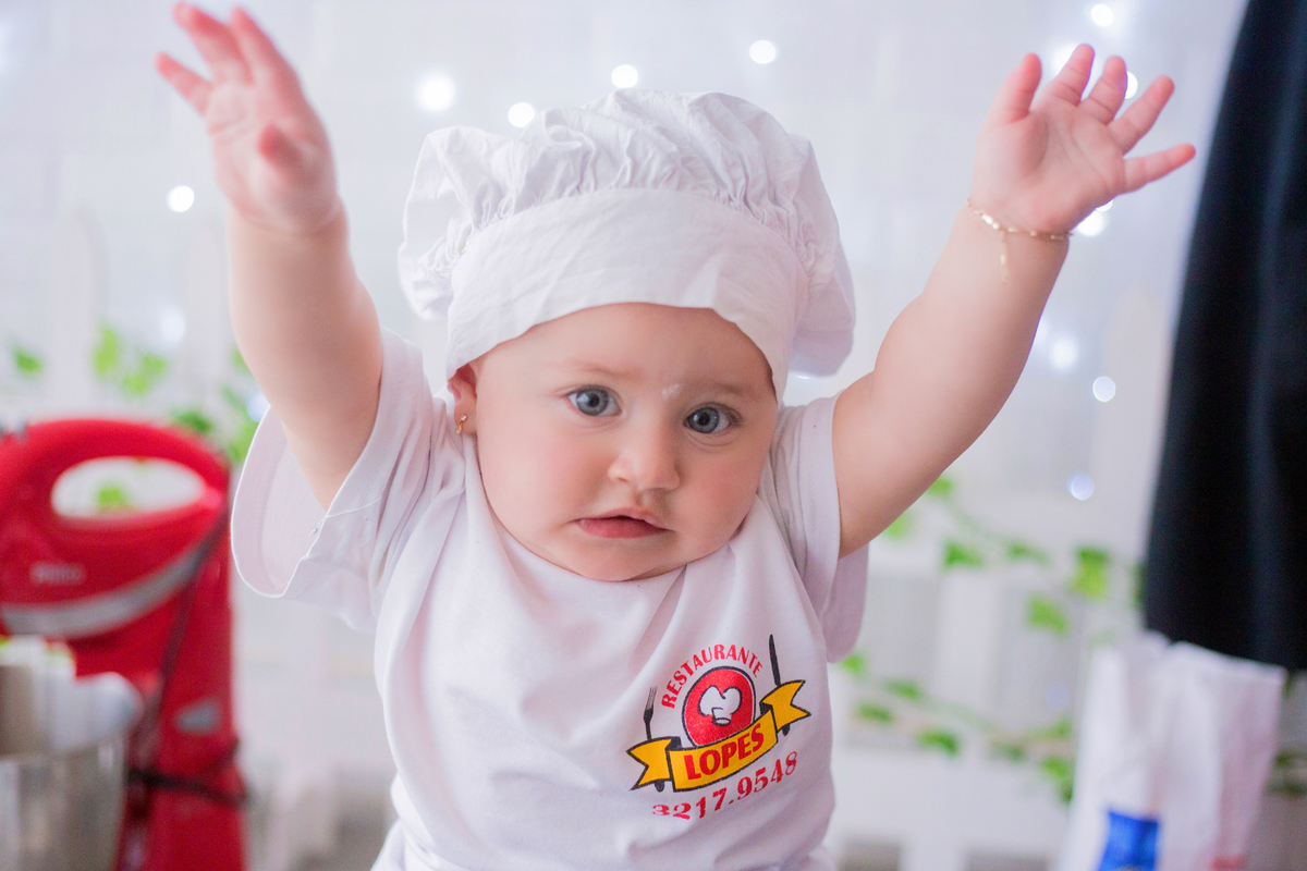 a bebê joga os braços para cima em sua sessão de acompanhamento mensal