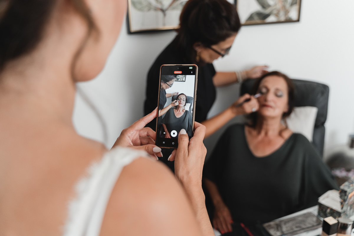 filha a fotografar a mae a ser maquilhada