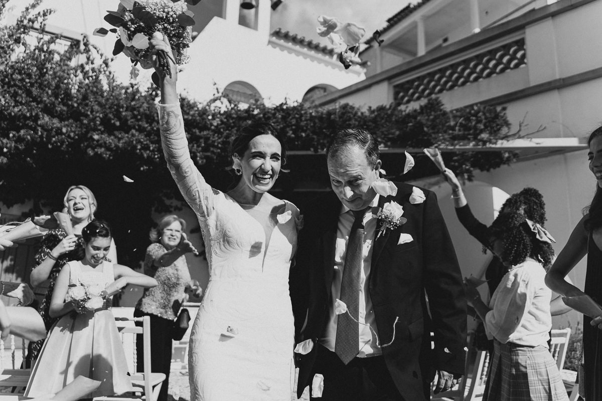 noivos a caminhar pelo corredor enquanto os convidados atiram as pétalas