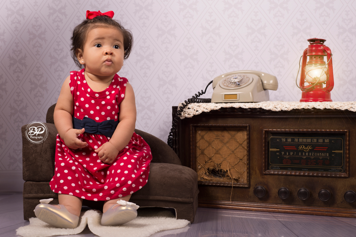 Danilo Pinezi Fotografia, ensaios infantis, ensaios temáticos, newborn, estúdio fotográfico, fotógrafo de família, ensaio vintage, bebê sentada no divã com telefone e rádio antigo