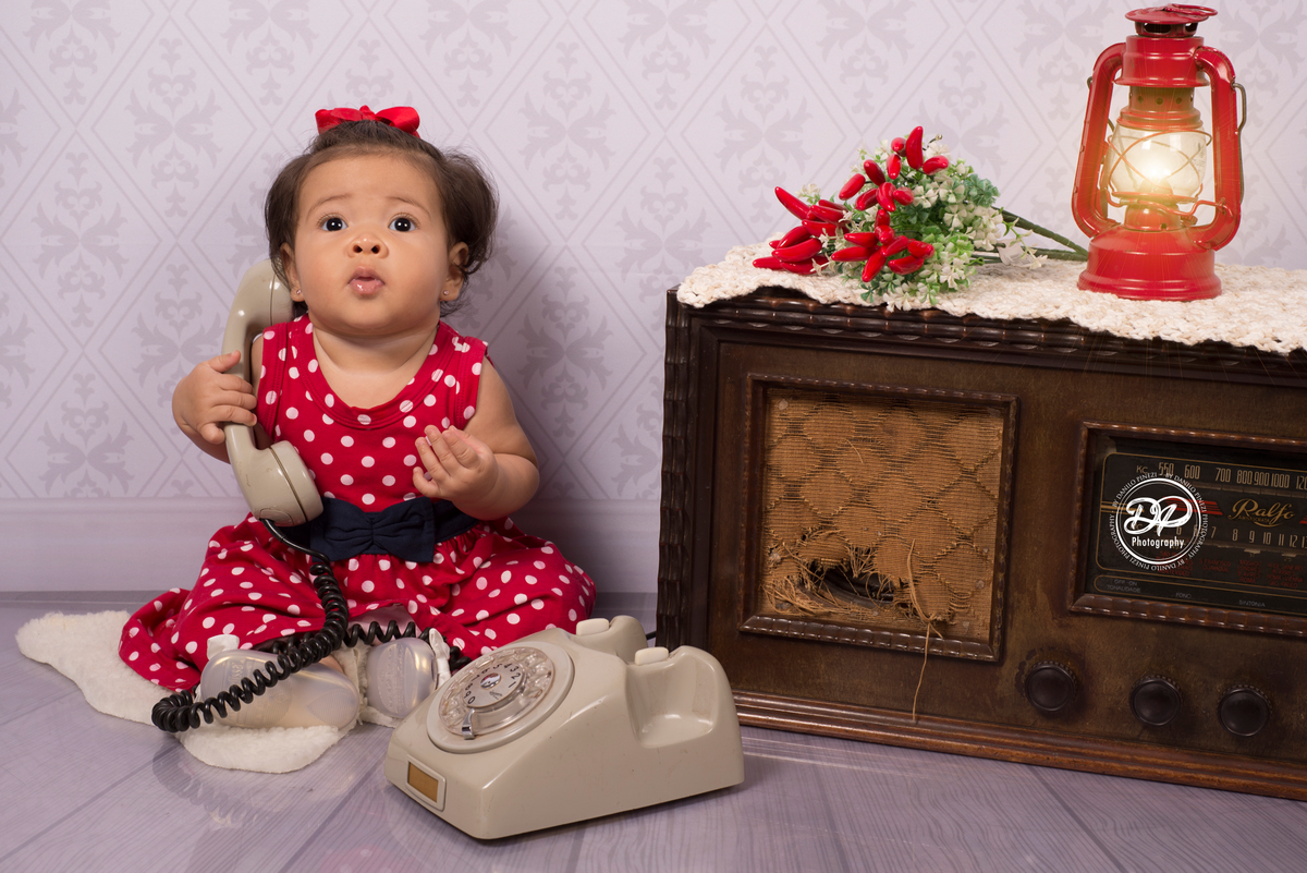 Danilo Pinezi Fotografia, ensaios infantis, ensaios temáticos, newborn, estúdio fotográfico, fotógrafo de família, ensaio vintage, bebê sentada no divã com telefone e rádio antigo
