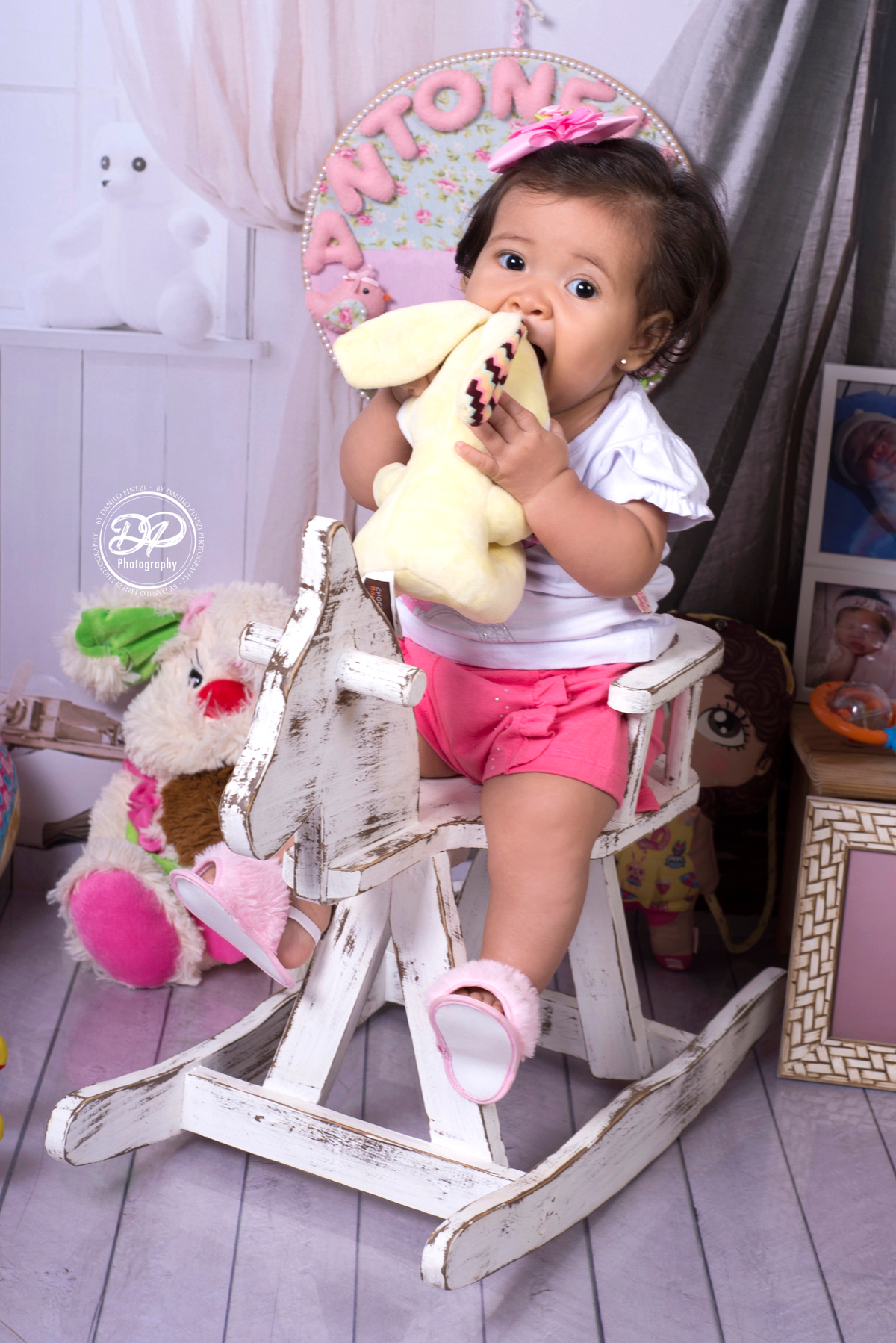 Sessão de bebê menina em estúdio, Tema quarto de Brinquedos, com Cavalo de madeira antigo e brinquedos e fotografias espalhados, realizado no estúdio Danilo Pinezi Fotografia