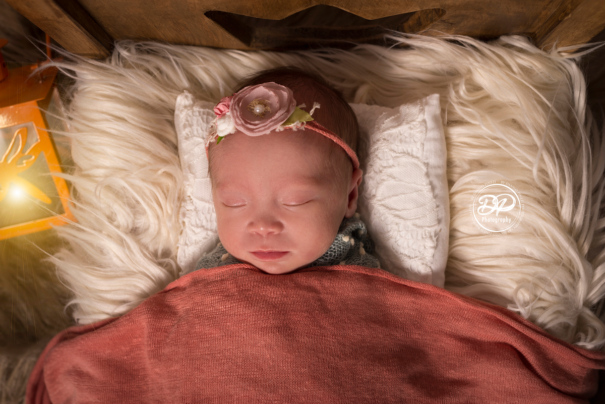 Bebê recém nascida, deitada em uma caminha dormindo tranquilamente em sessão newborn realizada no Estúdio Danilo Pinezi Fotografia em Bariri