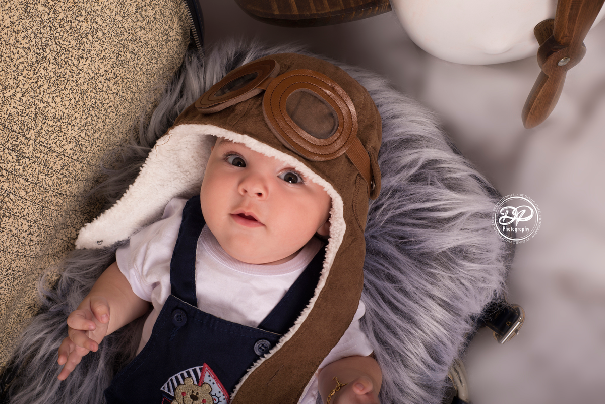 Sessão aviador de menino em estúdio, com avião jumbo, cachecol vermelho, touca de aviador e mala de viagem retrô, realizado no estúdio Danilo Pinezi Fotografia em Bariri