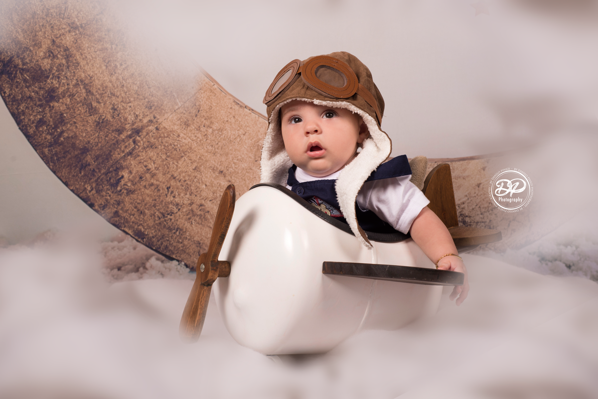 Sessão aviador de menino em estúdio, com avião jumbo, cachecol vermelho, touca de aviador e mala de viagem retrô, realizado no estúdio Danilo Pinezi Fotografia em Bariri