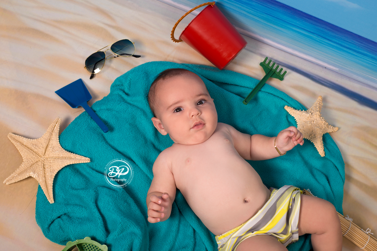 Ensaio menino tema Praia/Verão, com itens e e fundo de praia, feito no estúdio Danilo Pinezi Fotografia em Bariri