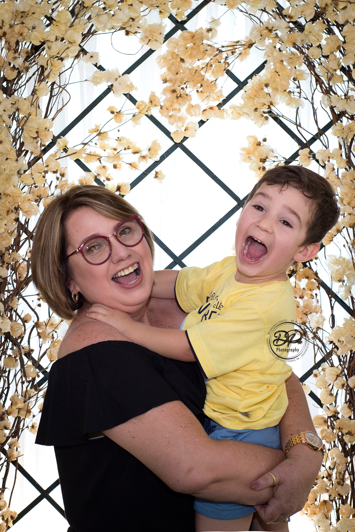 Neto abraçando a vovó com fundo de flores  em ensaio família  externo feito em bariri/ SP.