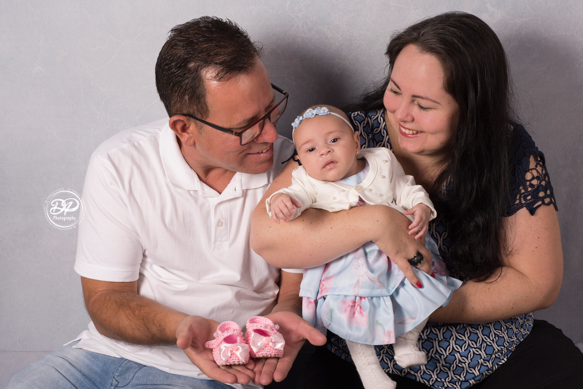Sessão de 2 meses de bebê menina deitada em balanço circular rústico, adornado com flores e água de cheiro, em sessão realizada no estúdio Danilo Pinezi Fotografia. Fotos com os pais