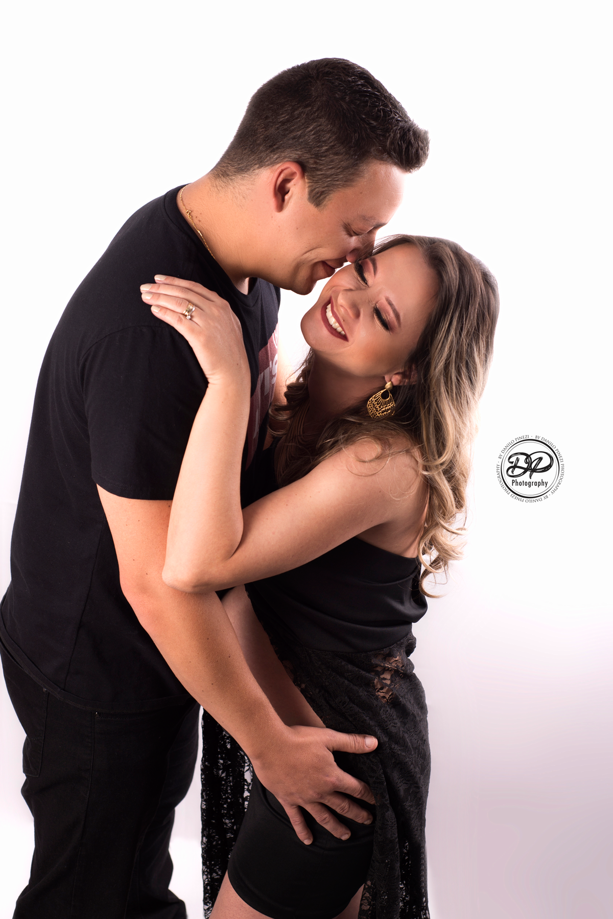 Ensaio gestante com casal vestido de preto, se abraçando em ensaio realizado no estúdio Danilo Pinezi Fotografia em Bariri.