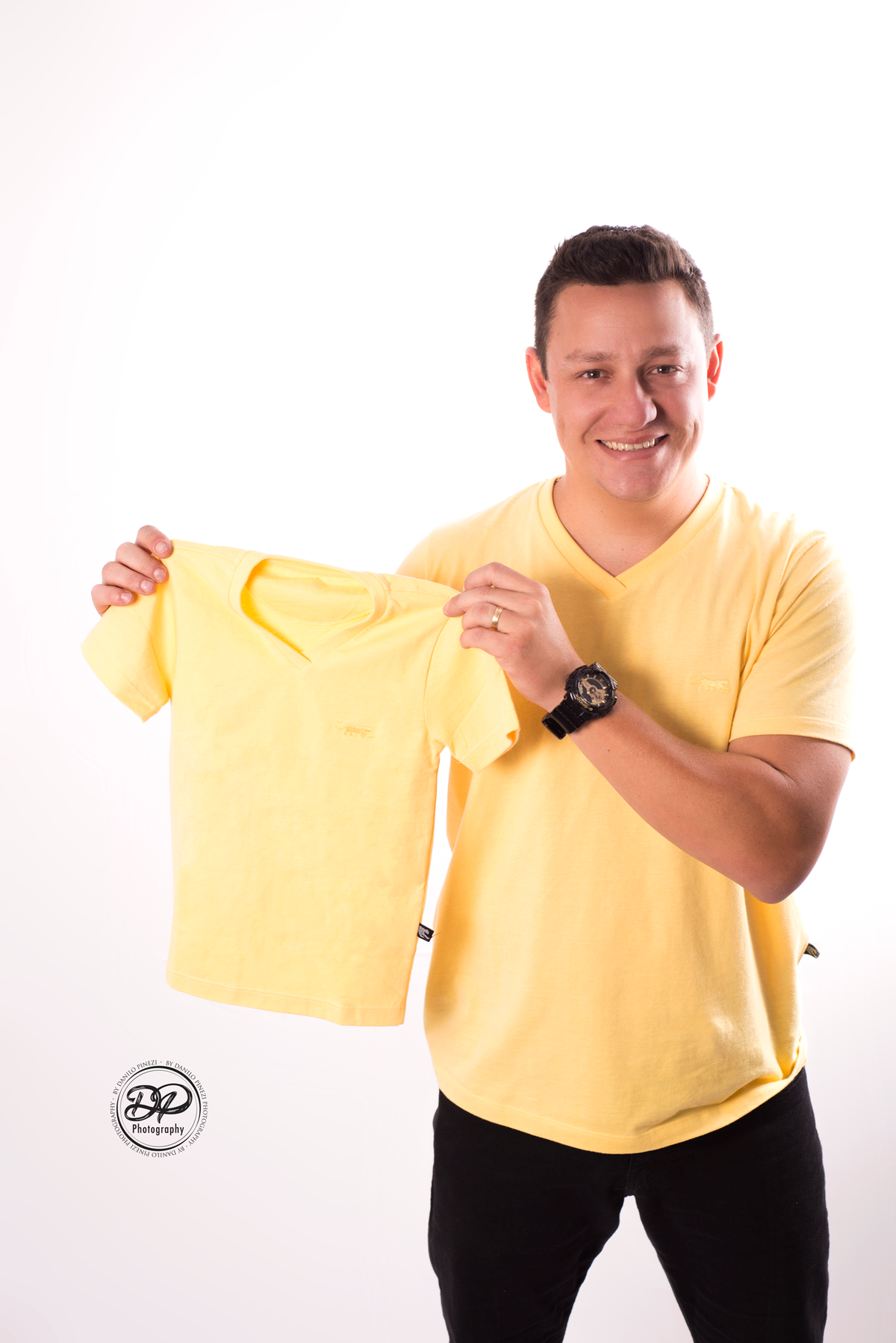 Ensaio gestante com o papai vestido de amarelo com camiseta tal pai tal filho, em ensaio realizado no estúdio Danilo Pinezi Fotografia em Bariri.