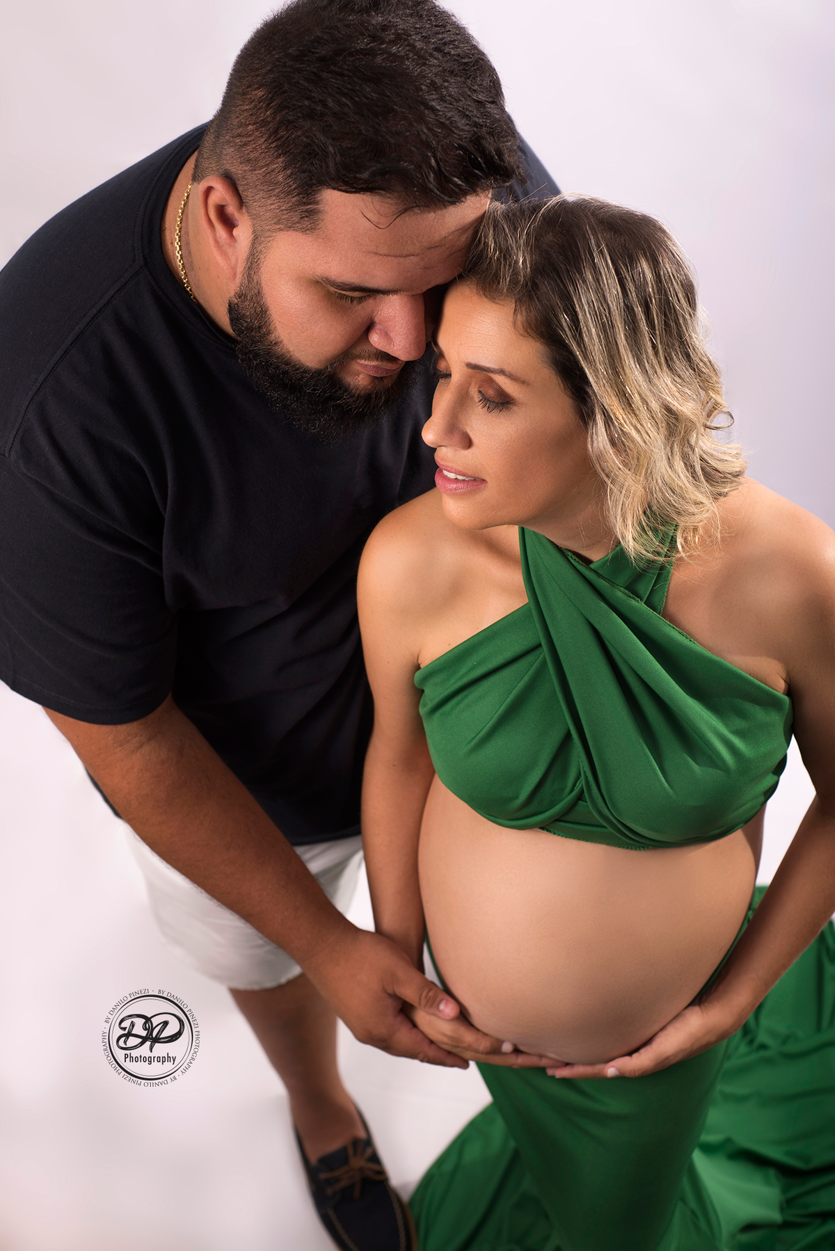 Ensaio gestante casal estúdio com pose romântica.