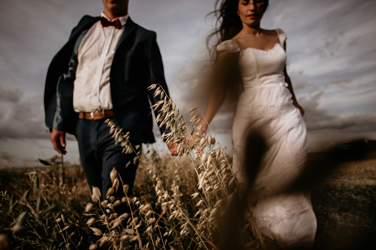 Foto movimiento. En el campo al atardecer. Pareja de novios. Vestido de novia caminando. Erika Fayolle