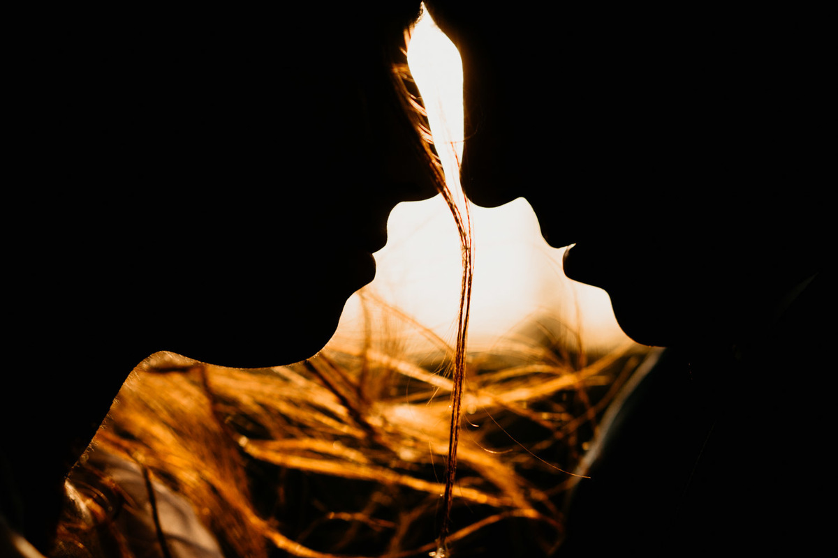 Silueta. Rostro de los novios en este retrato de pareja. Atardecer. Rayos de sol en el cabello de la novia. Erika Fayolle