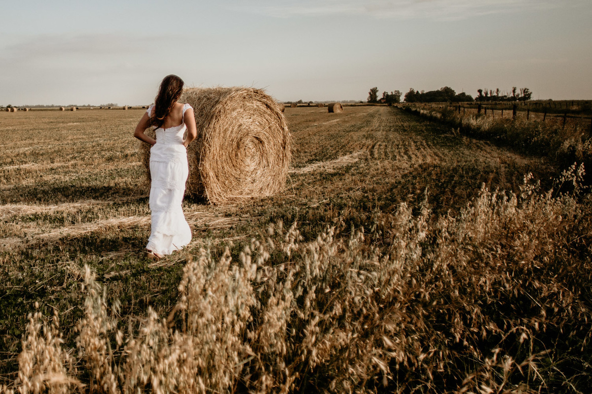 Novia en el campo de trigo. Vestido de novia blanco al atardecer . Erika Fayolle