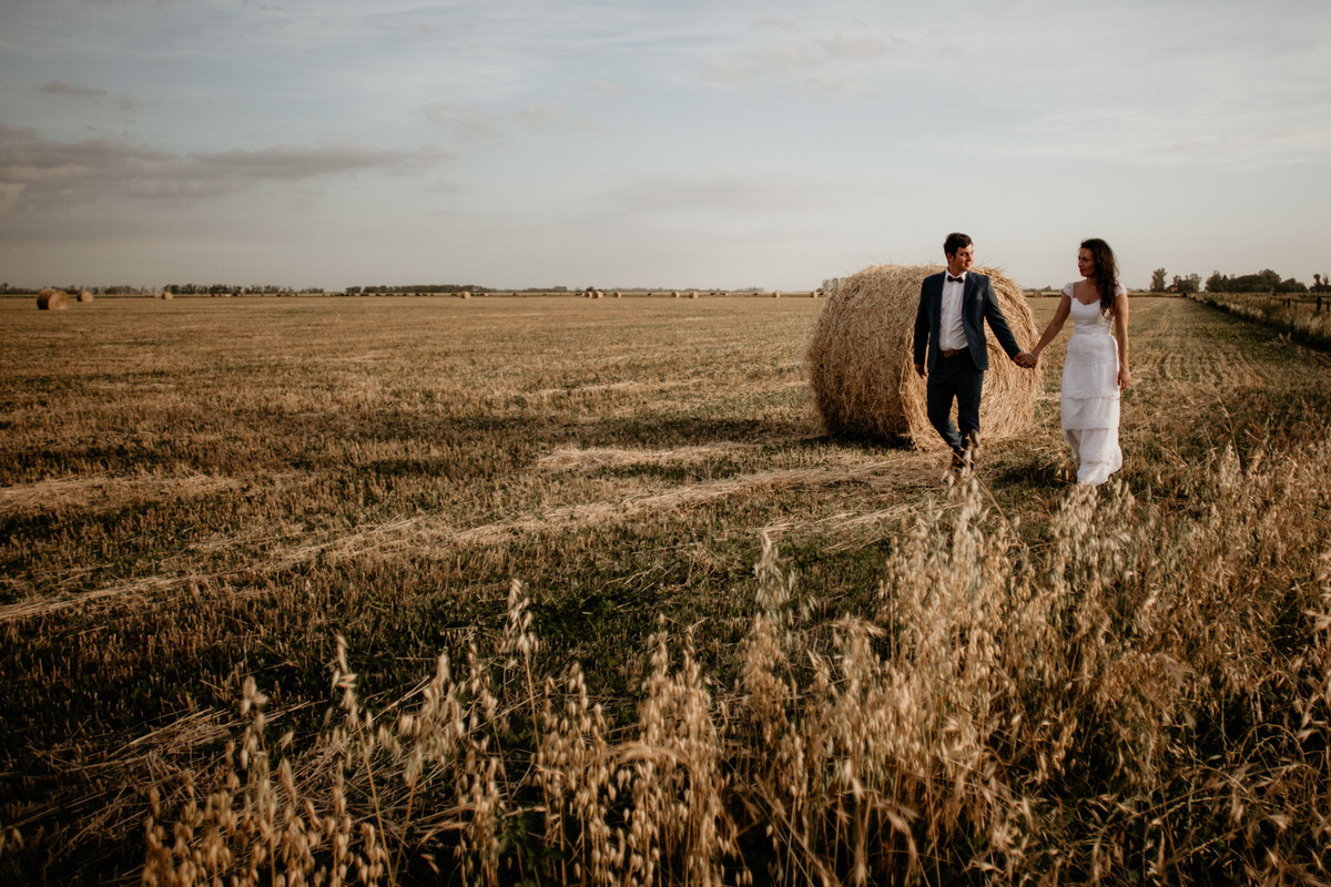 Pareja disfrutando la tarde de sol. Caída de la tarde en el trigal. Novia con traje de novios. 