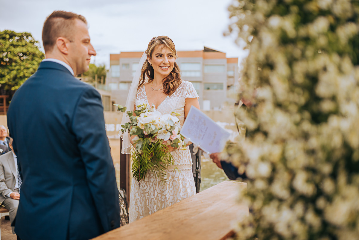 registro fotográfico de um casamento em Vitória-ES, Espírito Santo, noivos olhando para o celebrante