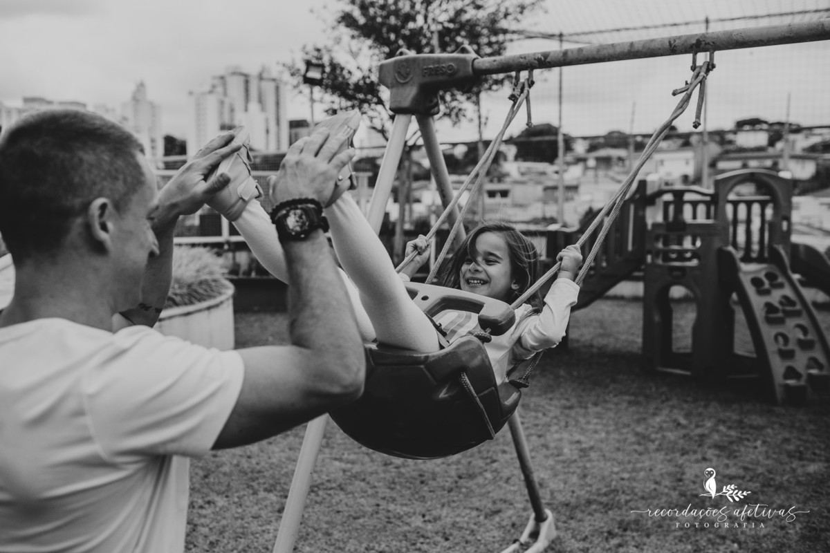 Pai empurrando menina balança