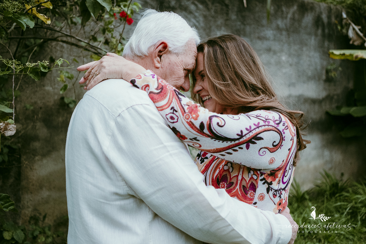 O casal compartilhando um momento de carinho durante o ensaio fotográfico em casa.