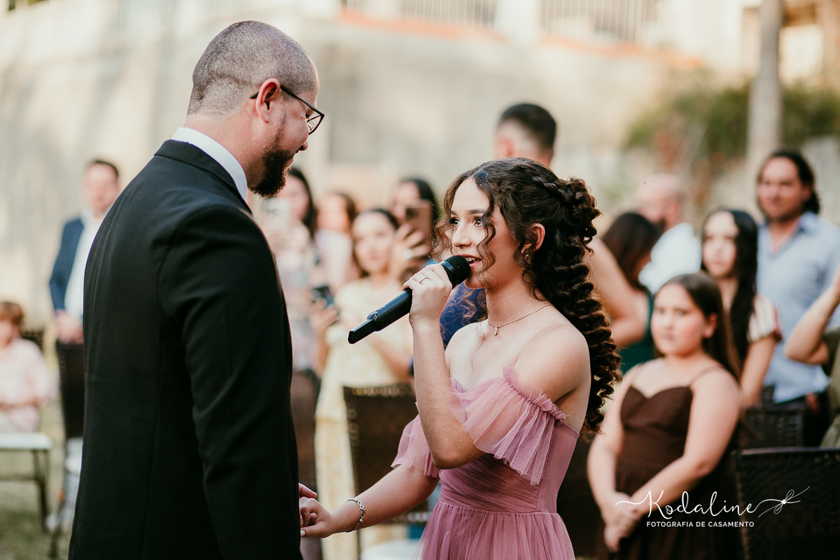 Filha mais velha entrando ao lado do pai e cantando durante a cerimônia de casamento