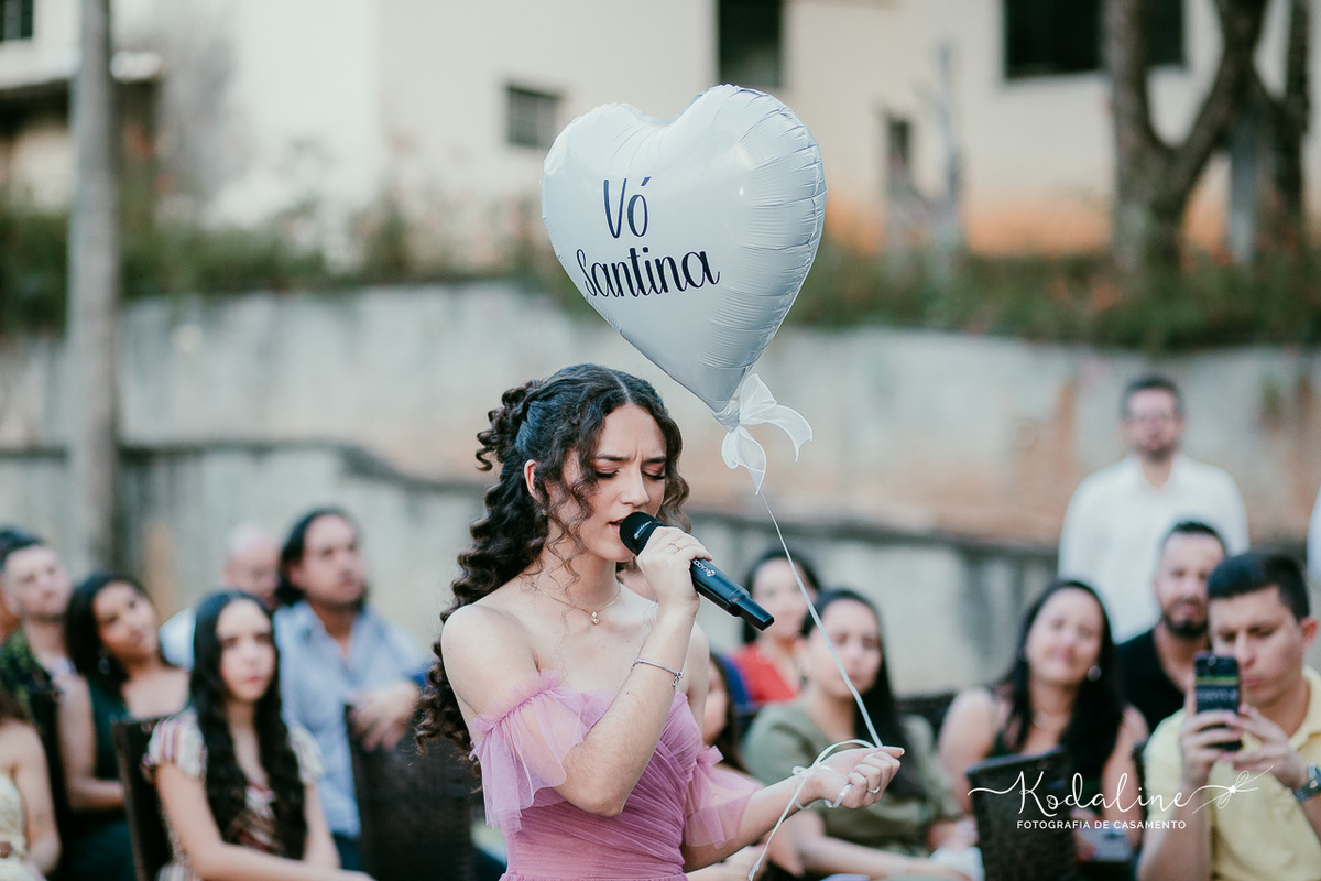 Filha entrando sozinha segurando um balão em formato de coração em homenagem à avó