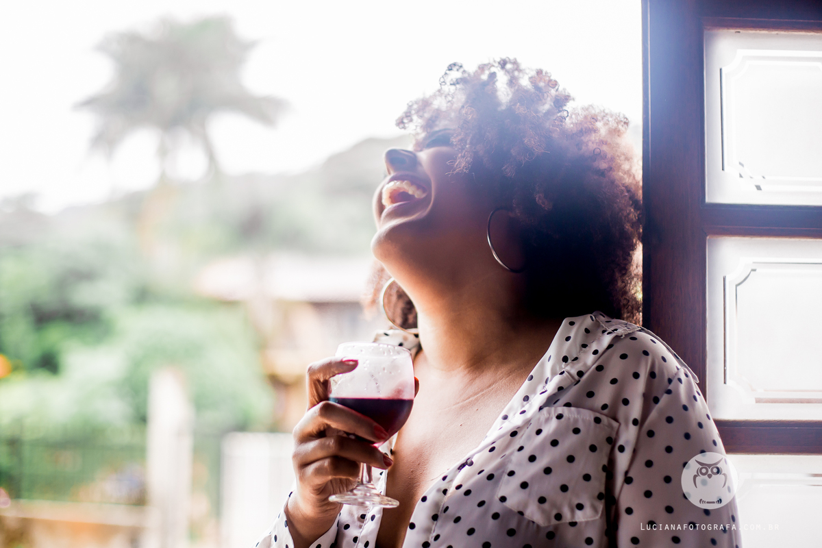 Ensaio feminino. Mulher tomando taça de vinho e sorrindo