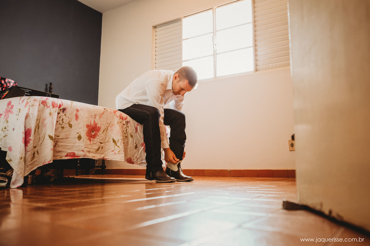 jaque risse, andre risse, estudio bebedouro, melhores fotografos, noivo calçando sua bota country sentado na cama com uma linda luz entrando pela janela aberta durante o making of