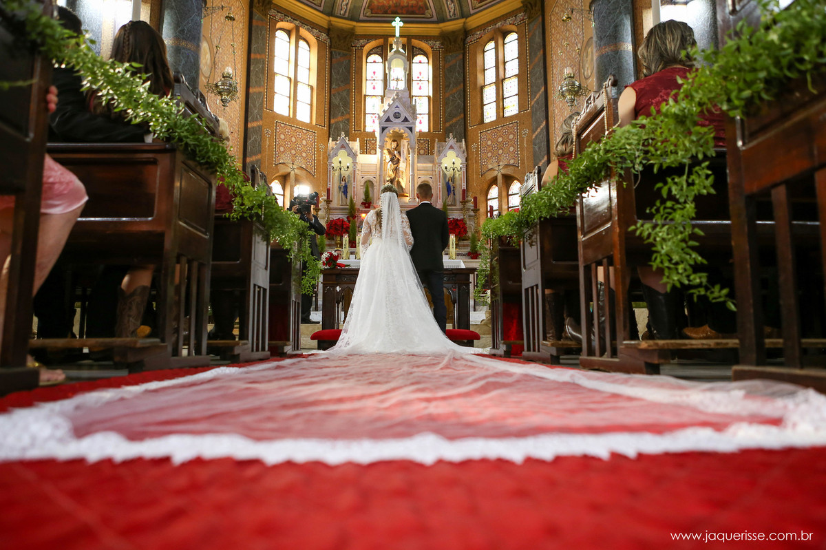 jaque risse, andre risse, estudio bebedouro, melhores fotografos,noivo e noiva no altar da igreja vistos de costas mostrando a longa calda do vestido