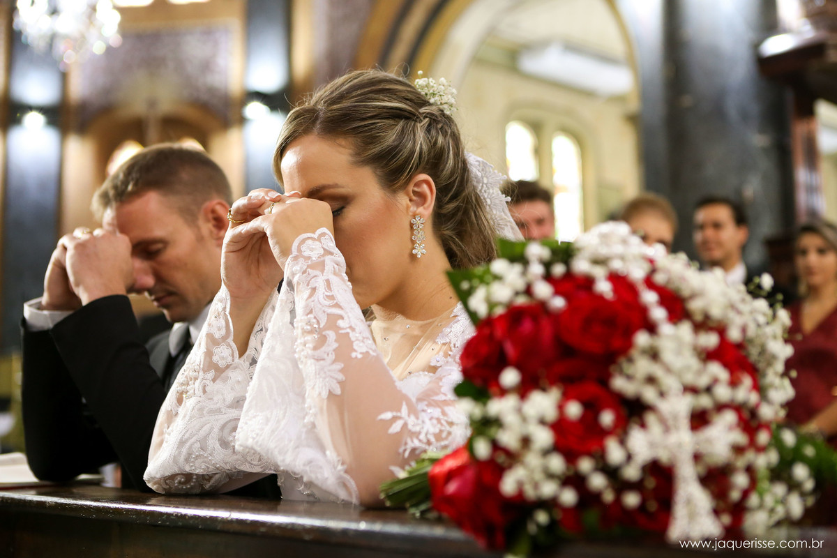 jaque risse, andre risse, estudio bebedouro, melhores fotografos, noiva e noivo ajoelhados no genuflexório orando com as cabeças baixas e as mãos na testa e detalhe do bouquet ao lado