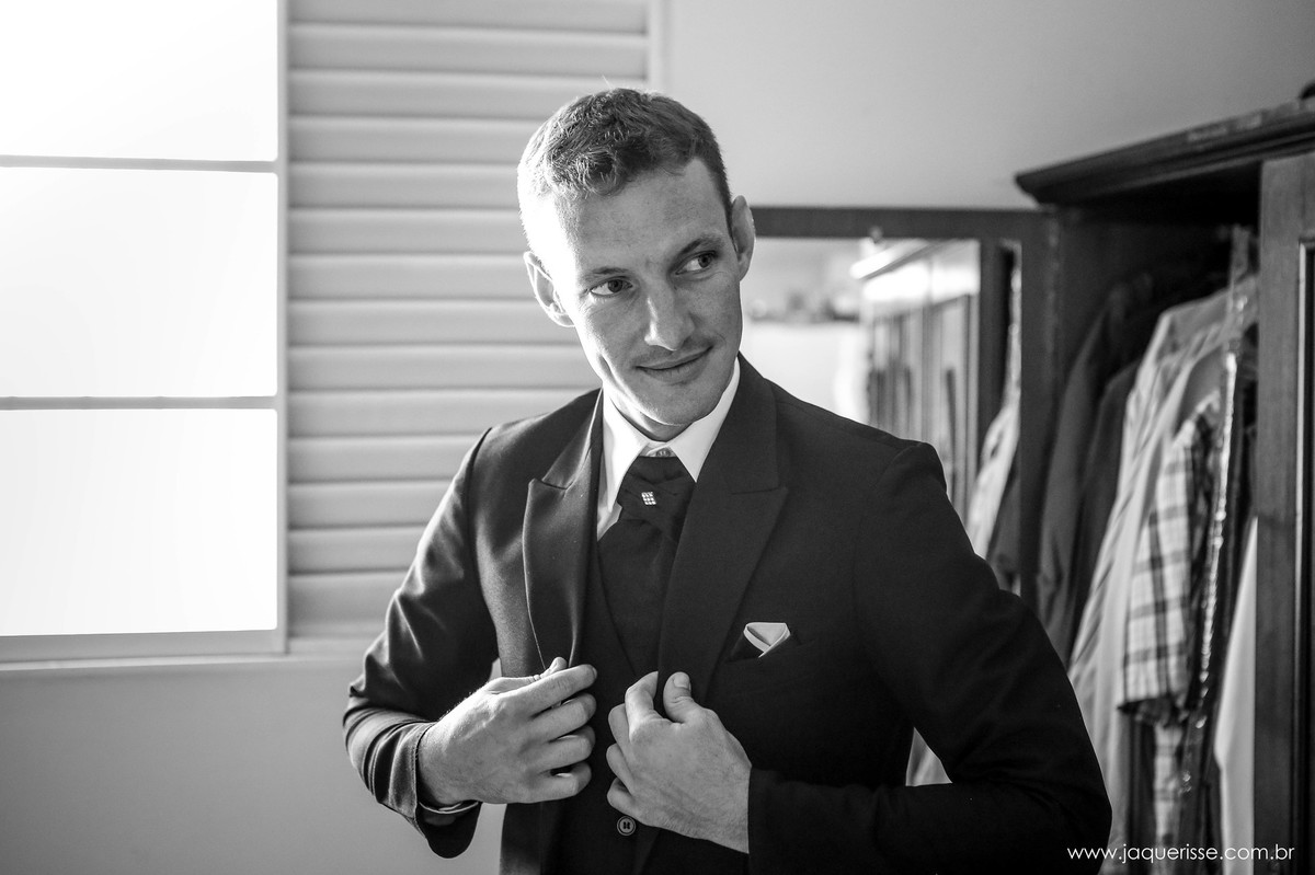 jaque risse, andre risse, estudio bebedouro, melhores fotografos, noivo olhando para o lado terminando de vestir o paletó durante o makin of