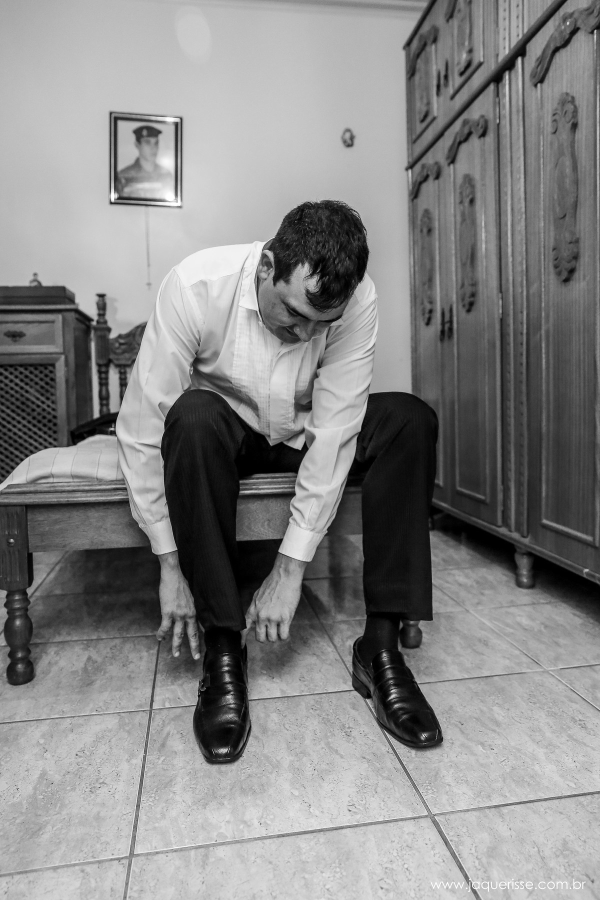 noivo sentado na cama calçando o sapato com as duas mãos durante o making of no click da fotógrafa de casamento Bebedouro SP Jaque Risse