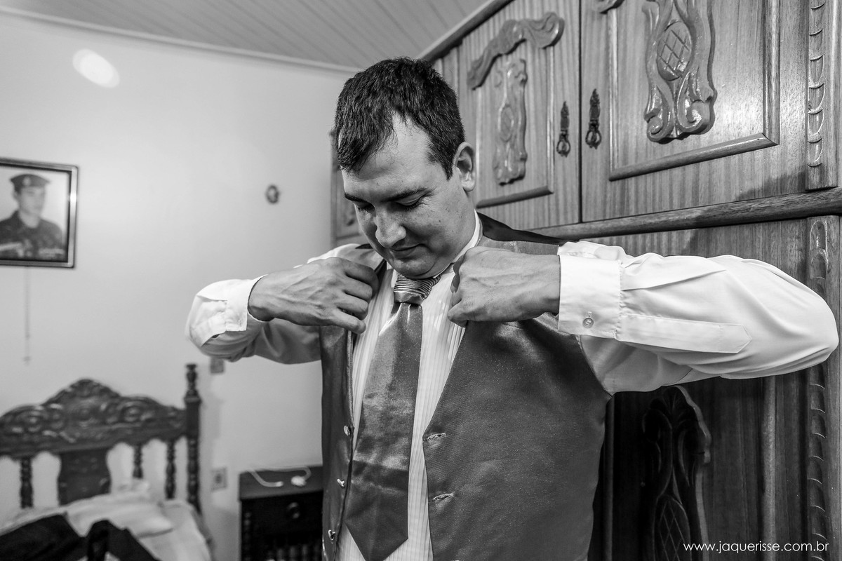 noivo vestindo o colete em frente ao gurda roupa durante o making of no click da fotógrafa de casamento Bebedouro SP Jaque Risse