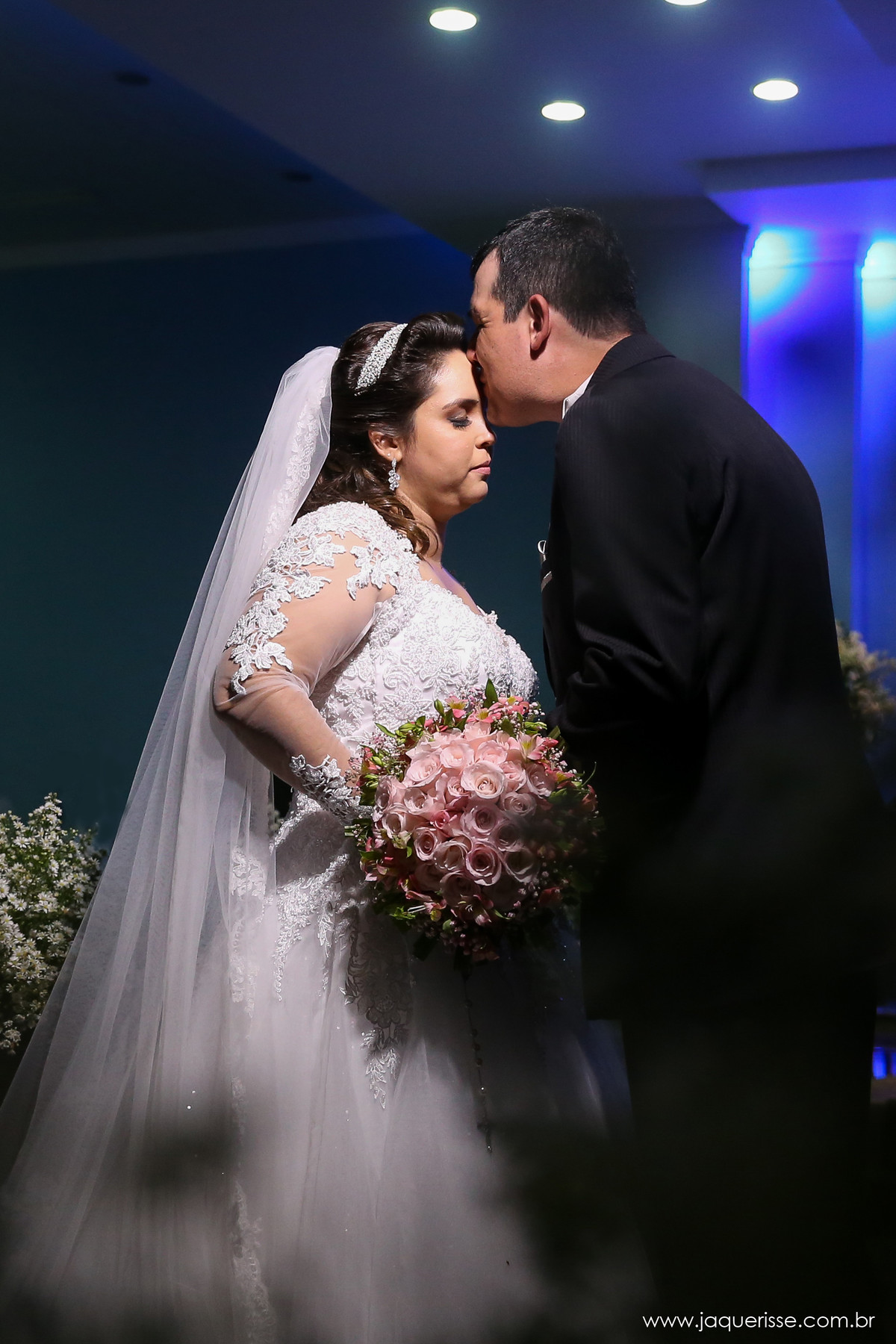 noivo beijando a testa da noiva em uma foto na penumbra com os noivos iluminados no click da fotógrafa de casamento Bebedouro SP Jaque Risse