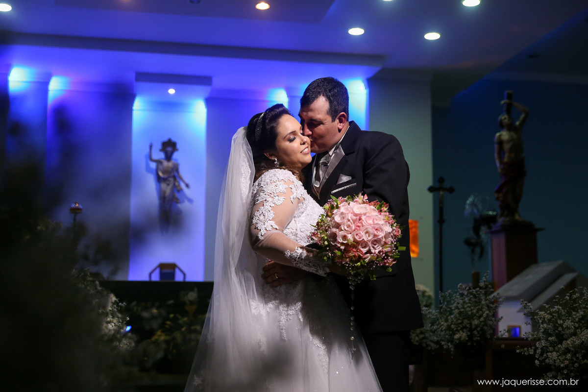 noivo beijando a testa da noiva em uma foto na penumbra com os noivos iluminados no click da fotógrafa de casamento Bebedouro SP Jaque Risse