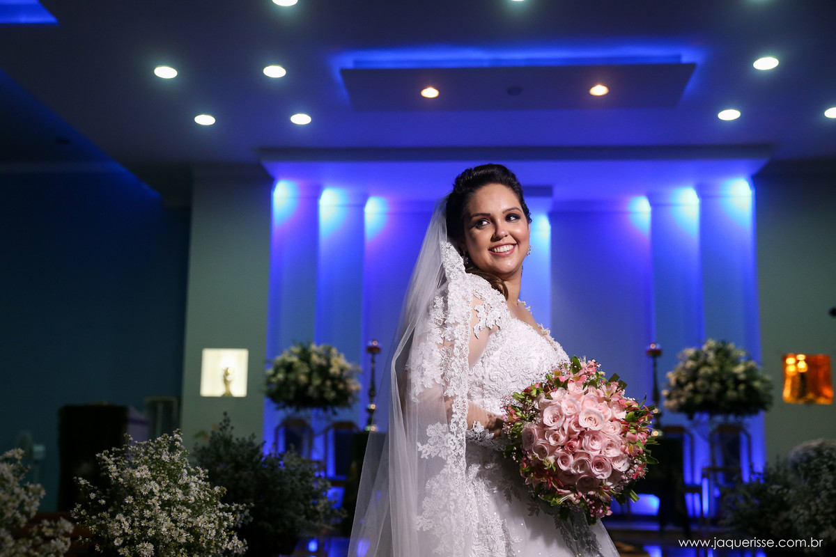 noiva sorridente posando para foto dentro da igreja com a iluminação reduzida no click da fotógrafa de casamento Bebedouro SP Jaque Risse